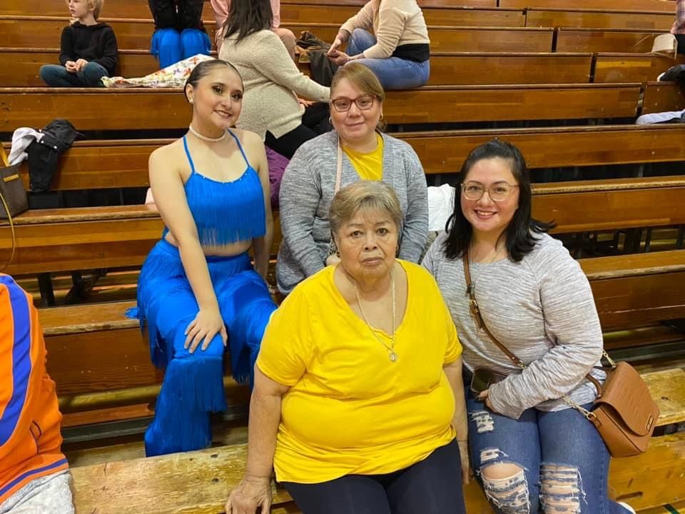 A group of women are sitting on wooden benches in a stadium.