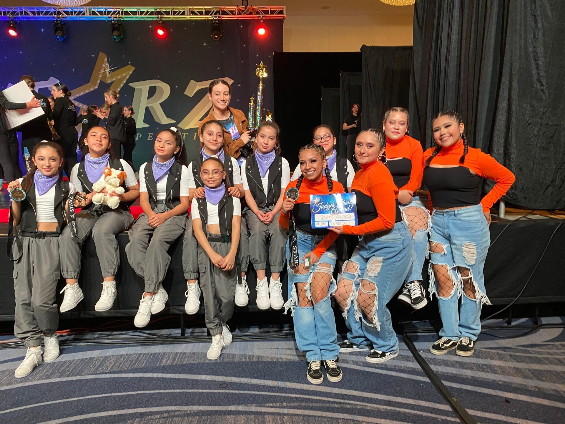A group of young girls are posing for a picture on a stage.