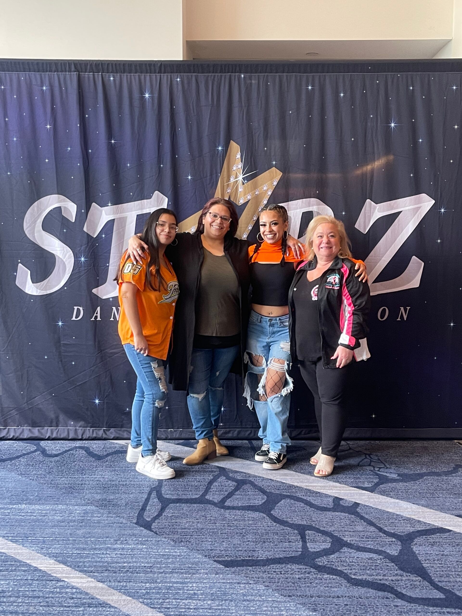 A group of women are posing for a picture in front of a starz sign.