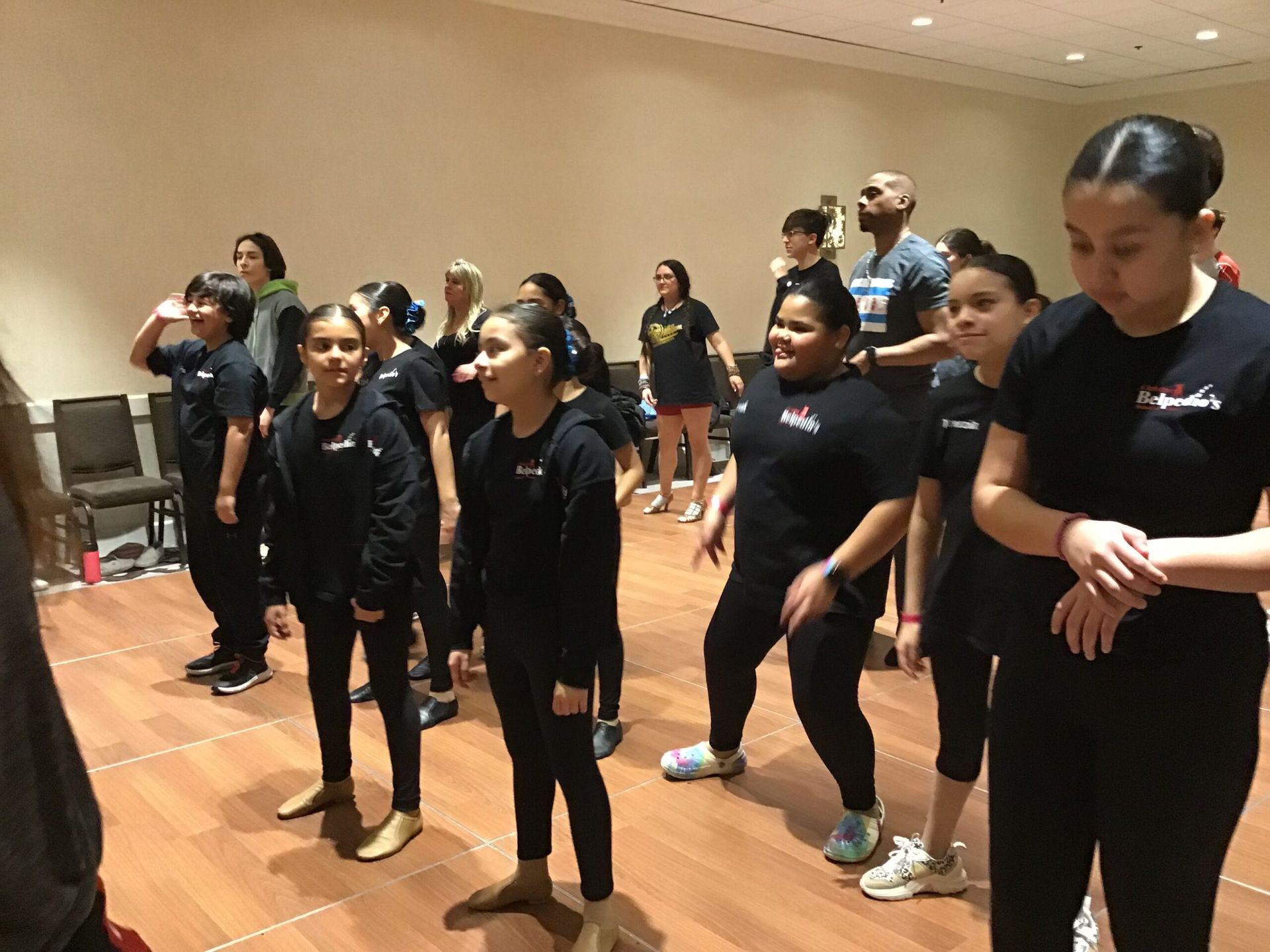 A group of people are standing on a wooden floor in a room.