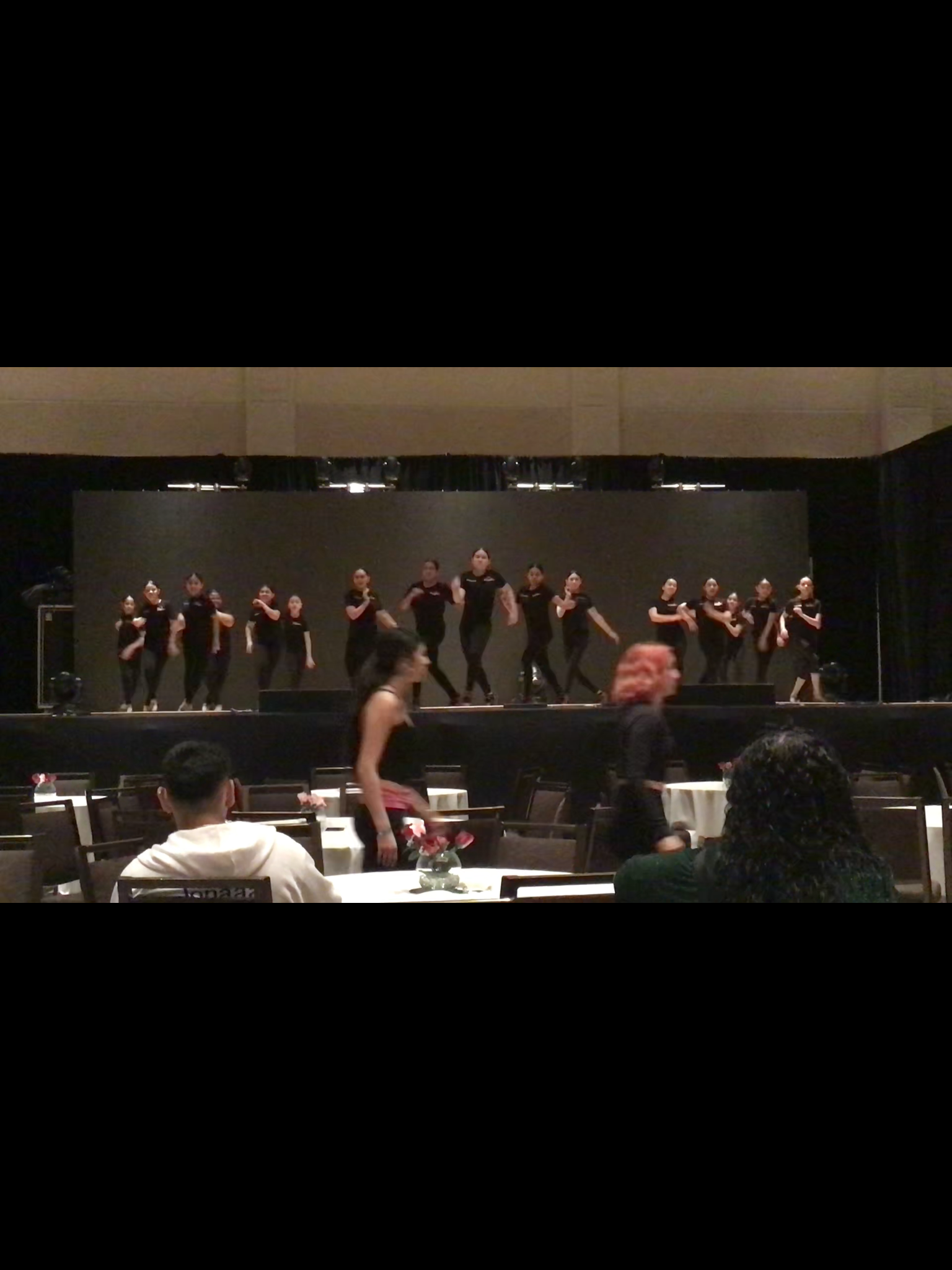 A group of people are dancing on a stage in front of a crowd.