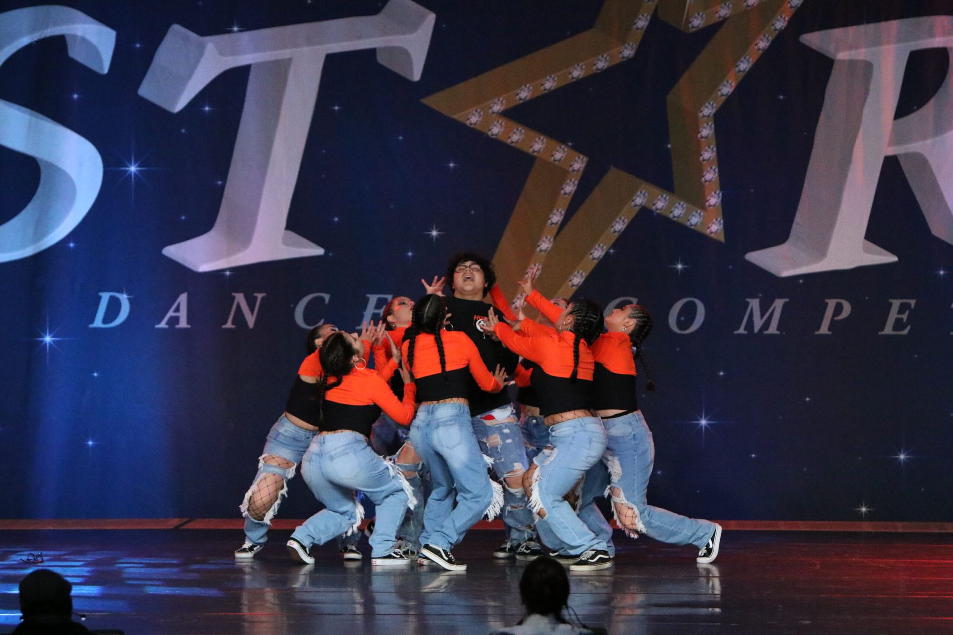 A group of dancers are performing in front of a star dance compe logo