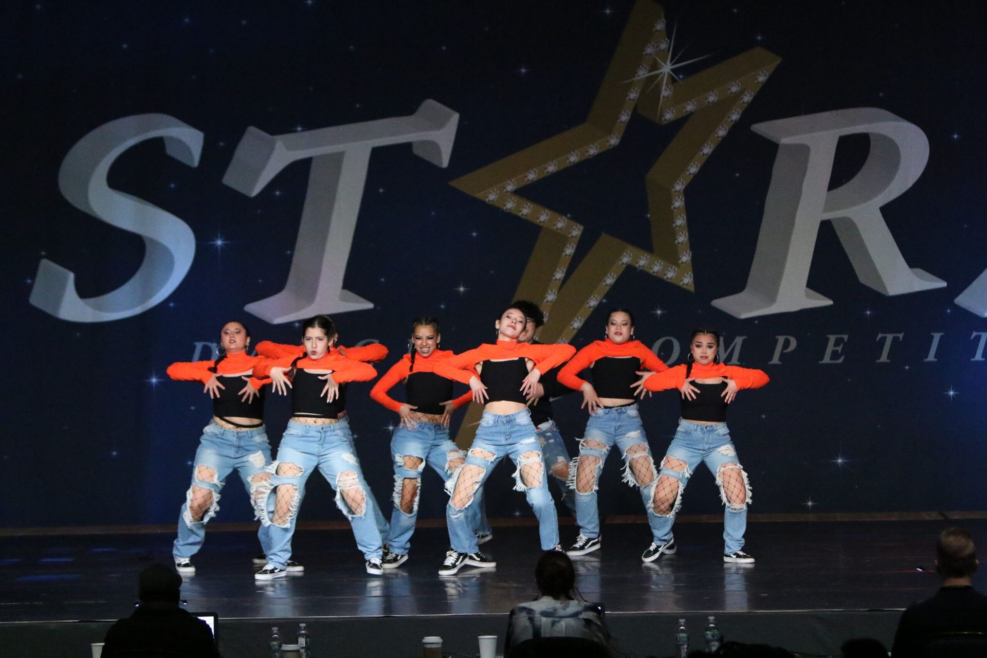 A group of young women are dancing in front of a star logo