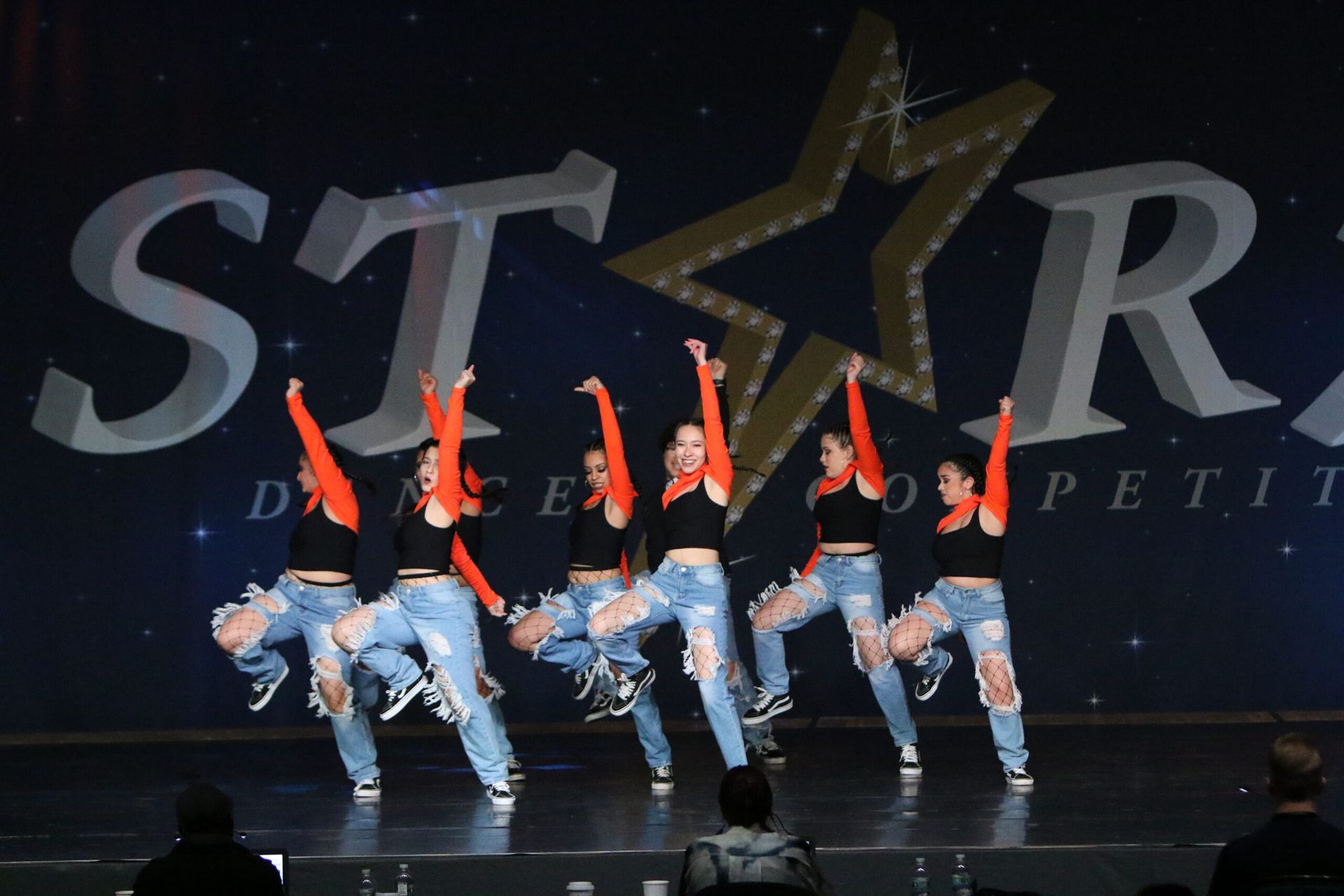 A group of dancers are performing in front of a star logo