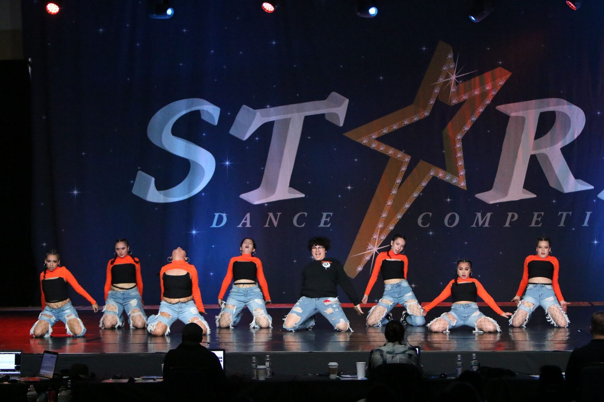 A group of dancers are performing in front of a star dance competition logo