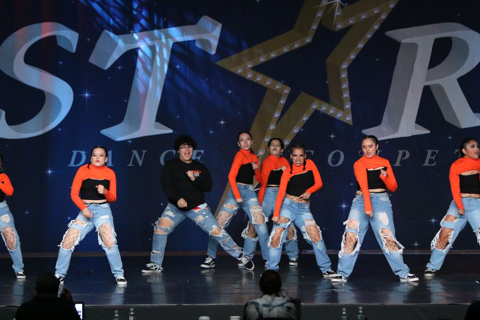 A group of young girls are performing on a stage in front of a sign that says star