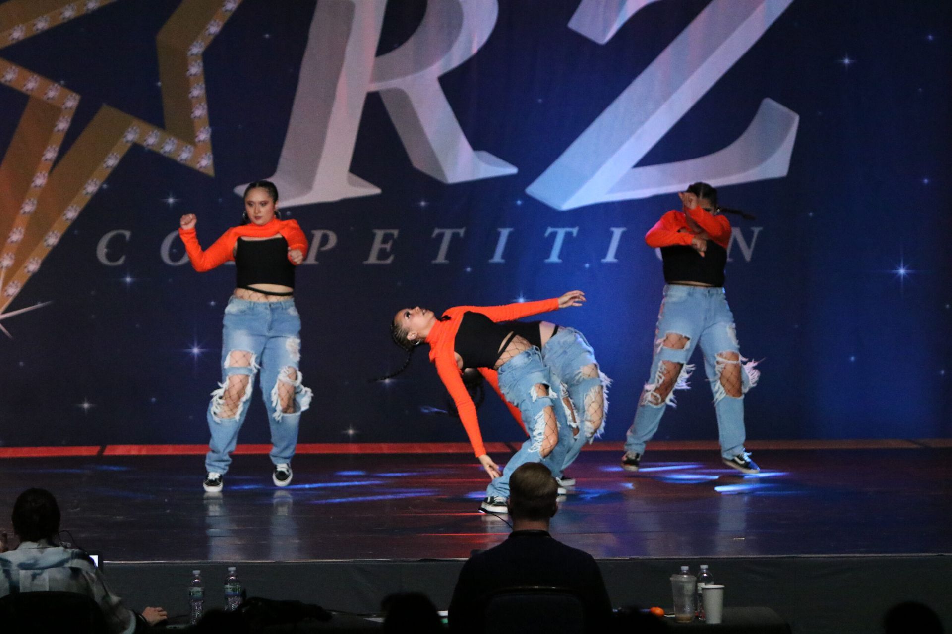 A group of dancers are performing in front of a sign that says competition