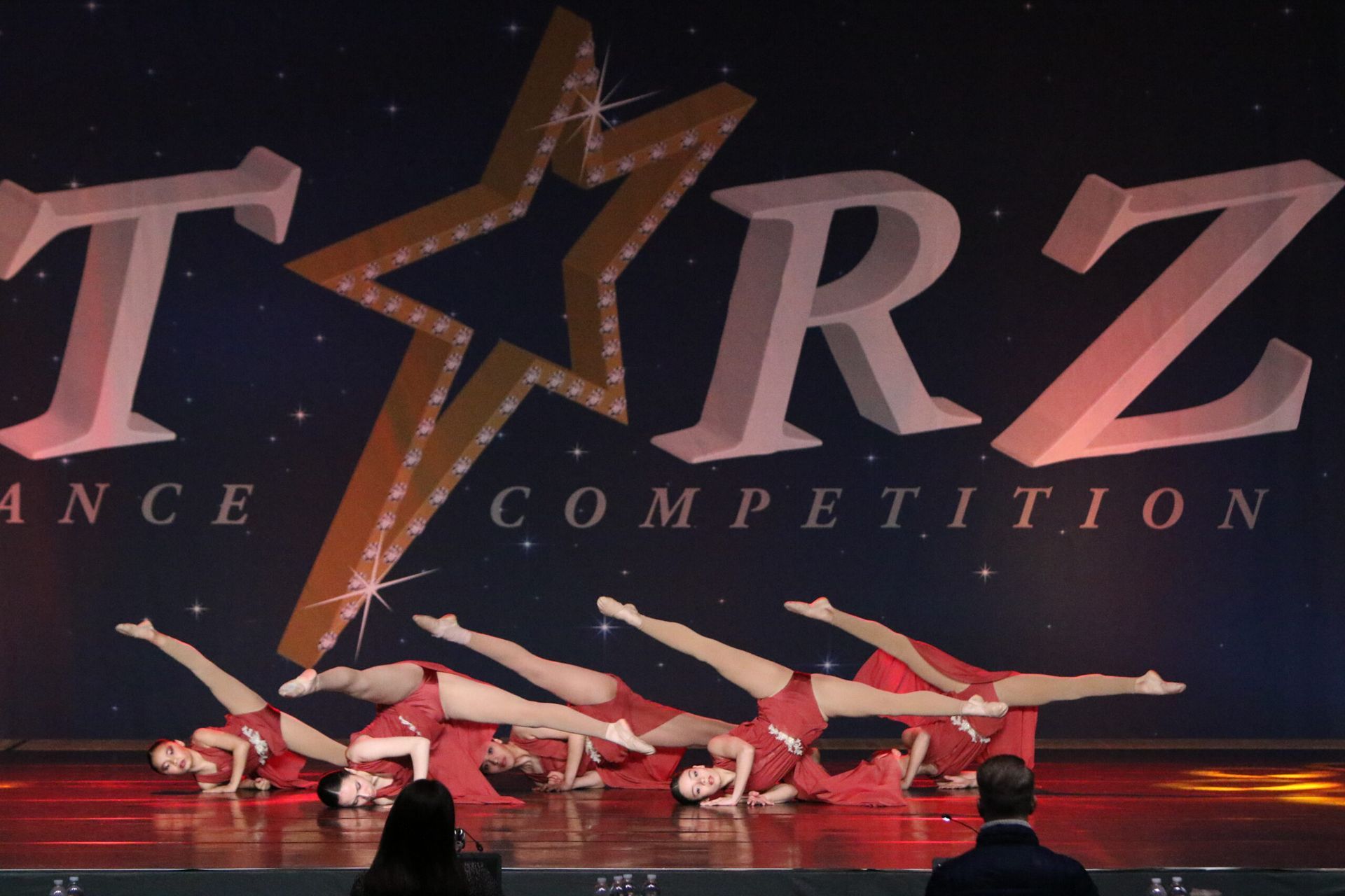 A group of dancers perform in front of a sign that says tarz competition