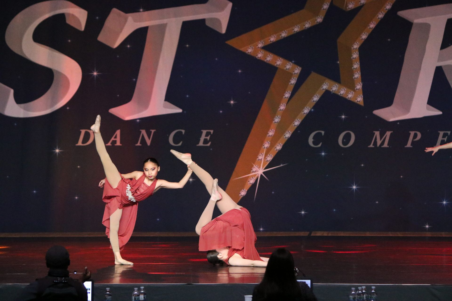 Two dancers perform on a stage in front of a sign that says dance compe