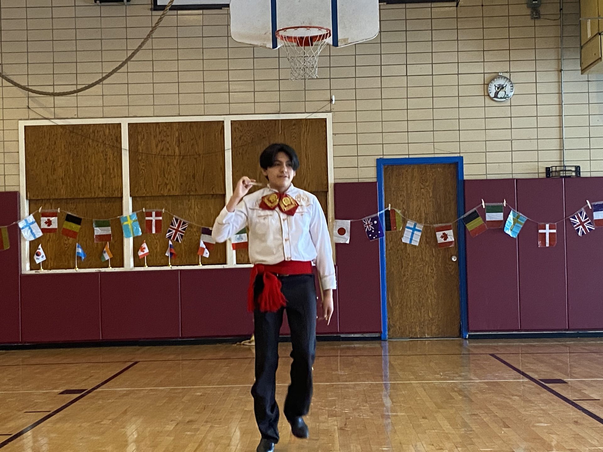 A man in a mariachi costume is walking in a gym.