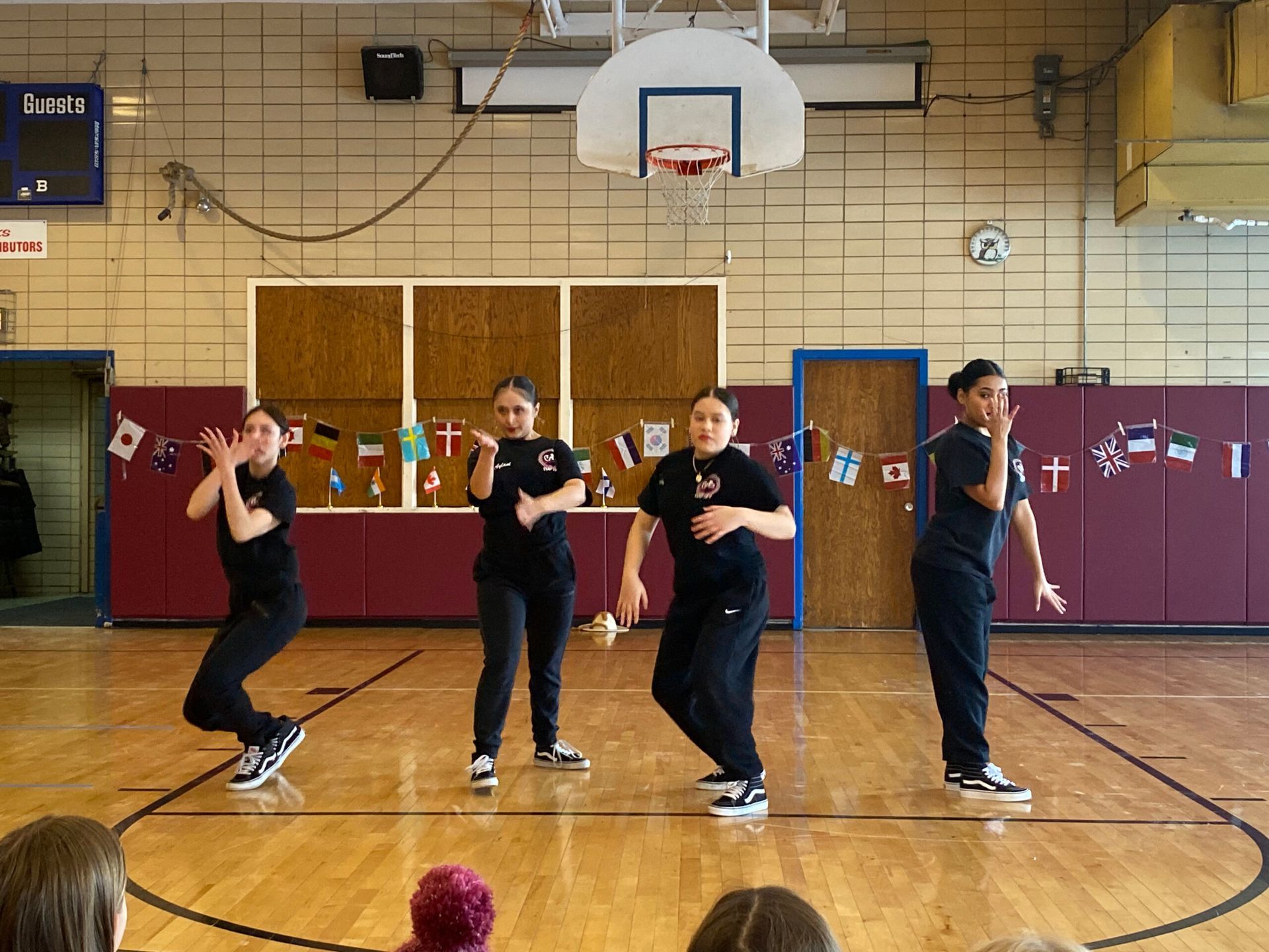 A group of young girls are dancing on a basketball court.
