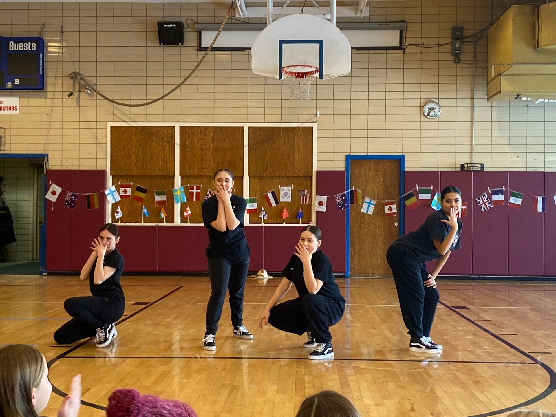 A group of girls are squatting on a basketball court.