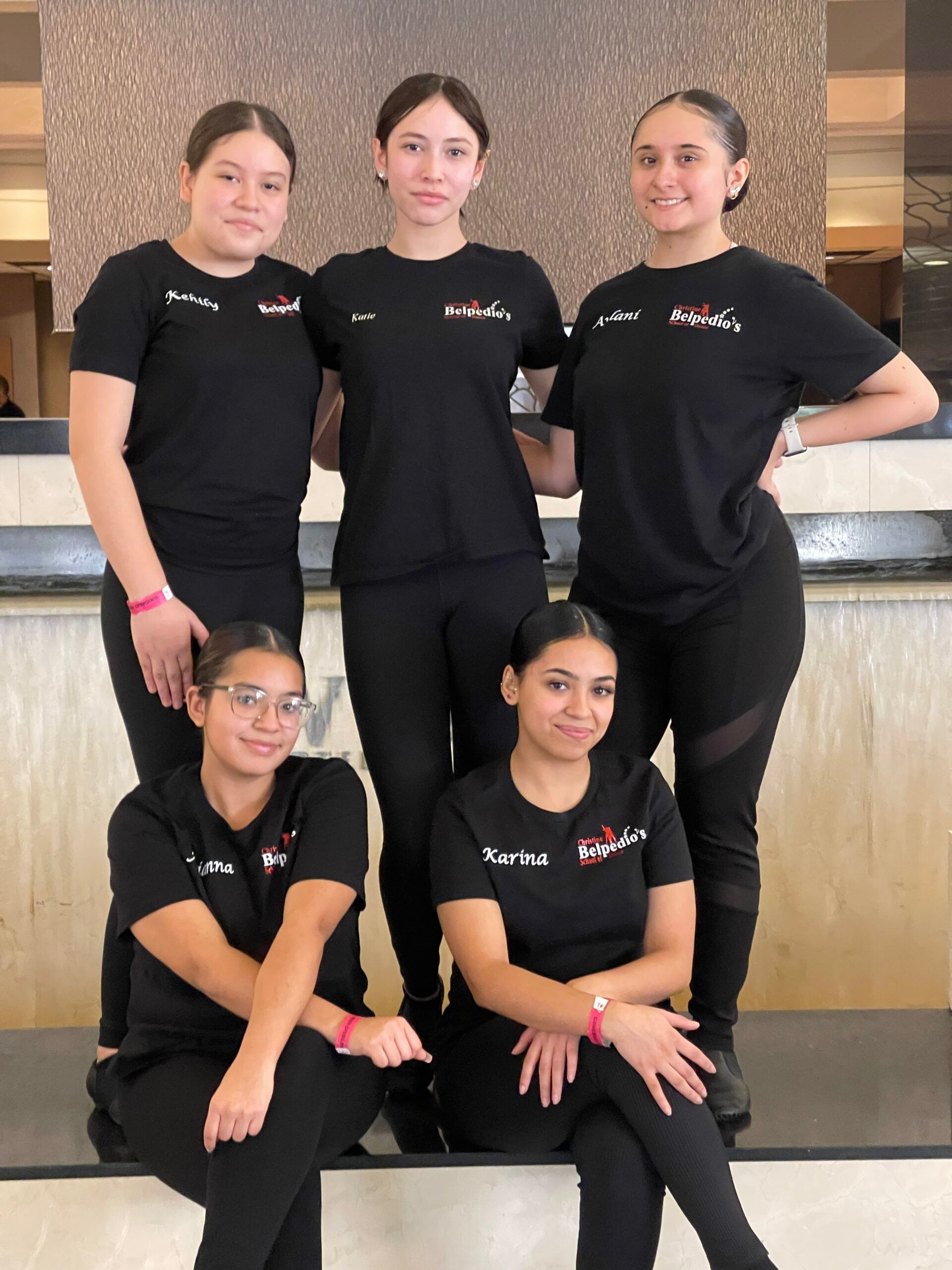 A group of young women wearing black shirts are posing for a picture