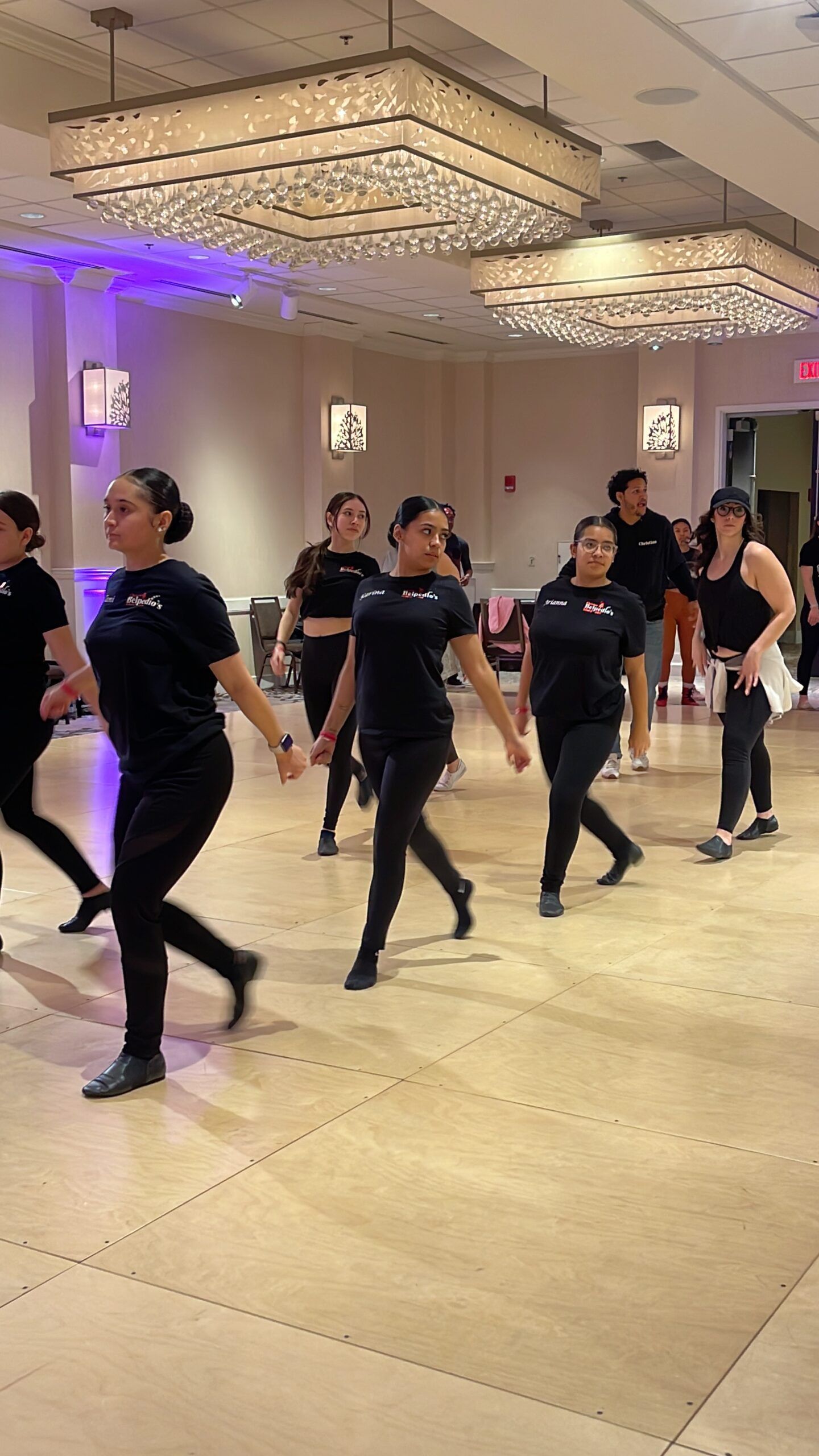 A group of women are dancing on a dance floor in a large room.