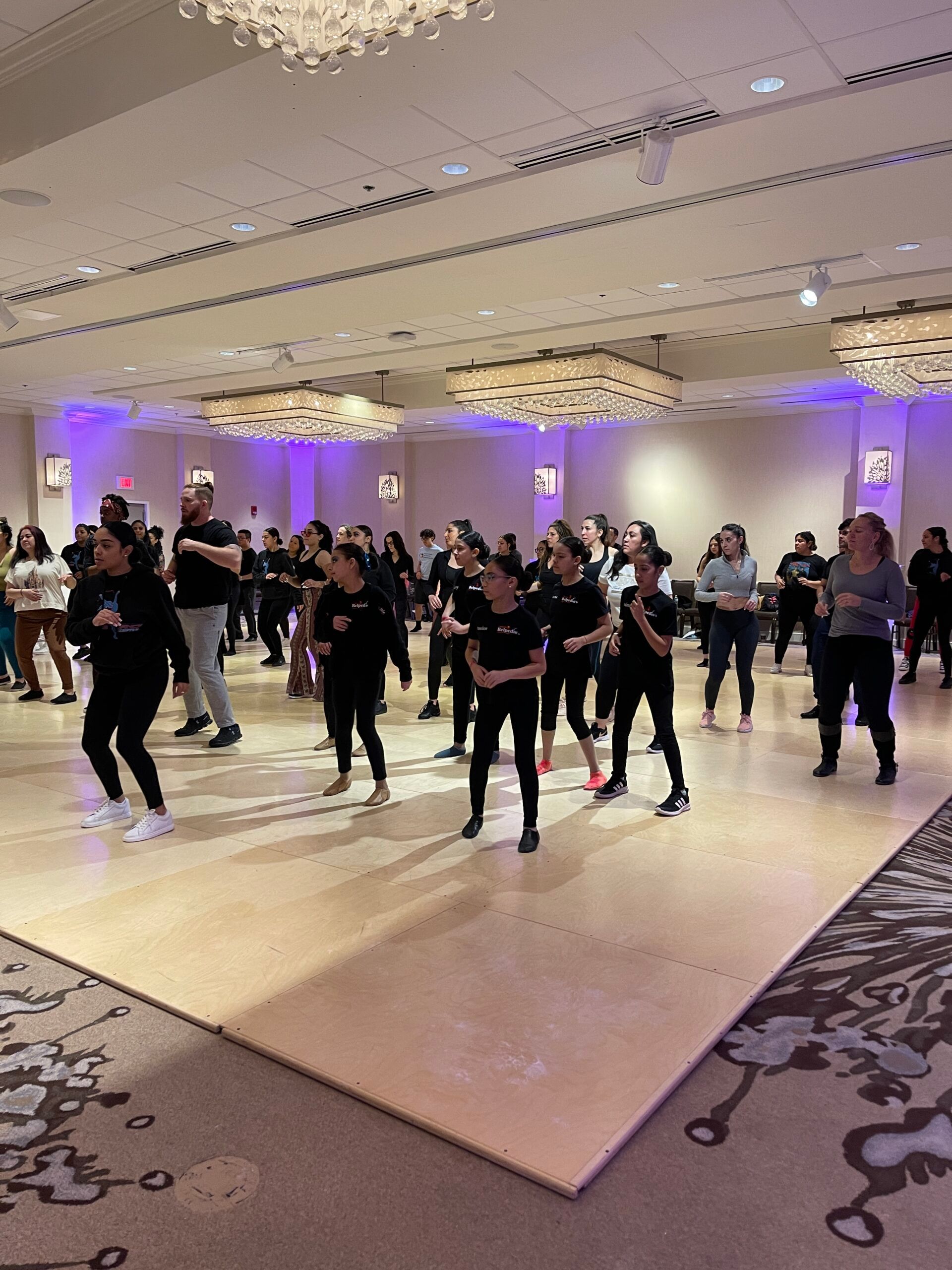 A large group of people are dancing in a large room.