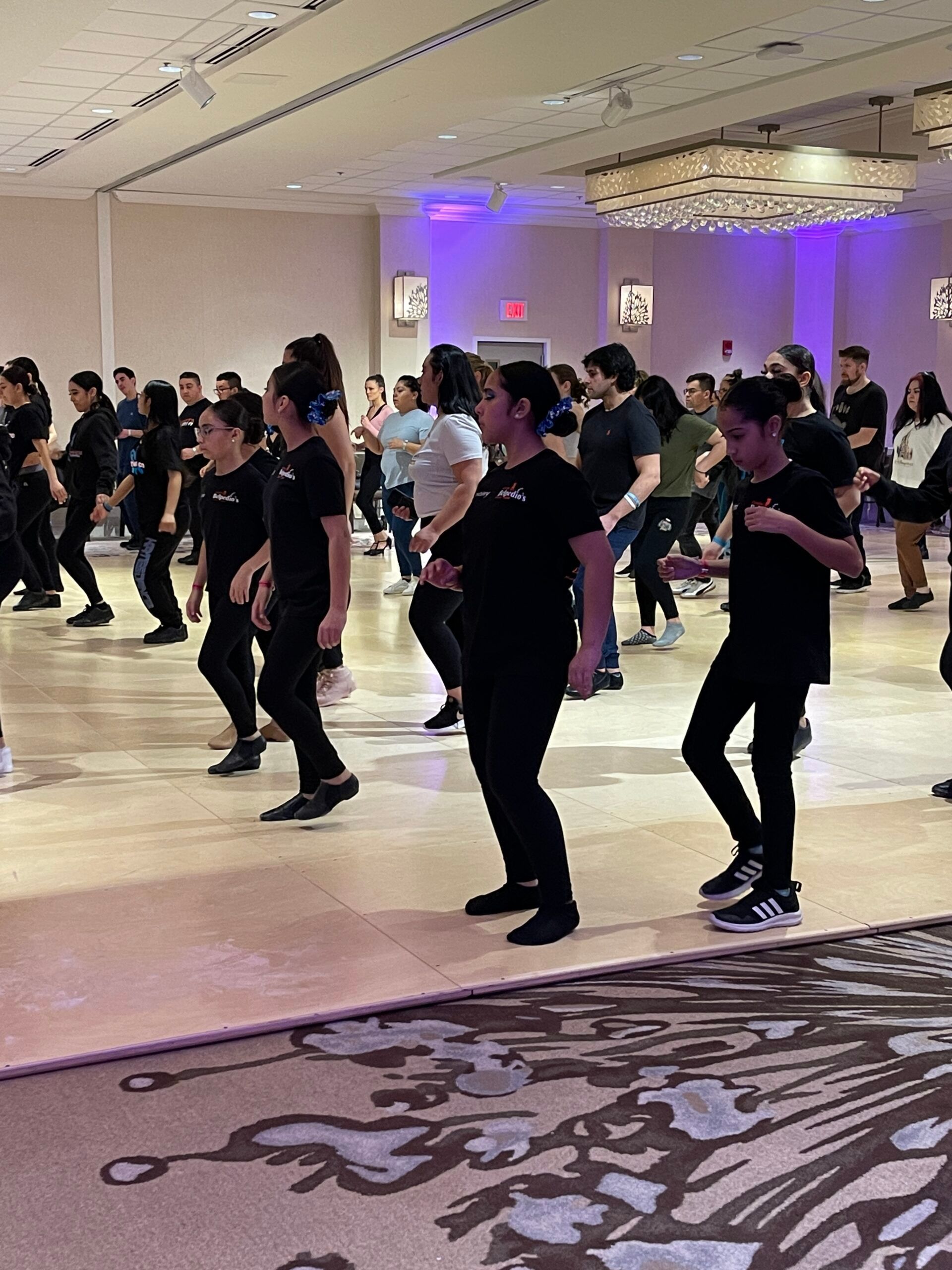 A group of people are dancing in a large room.