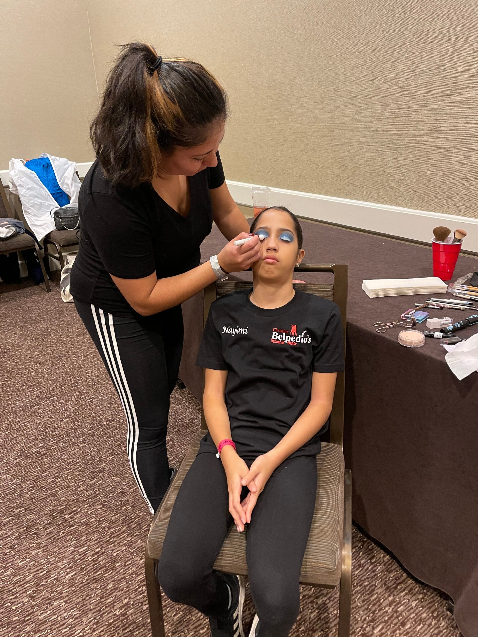 A woman is applying makeup to a young girl 's face.