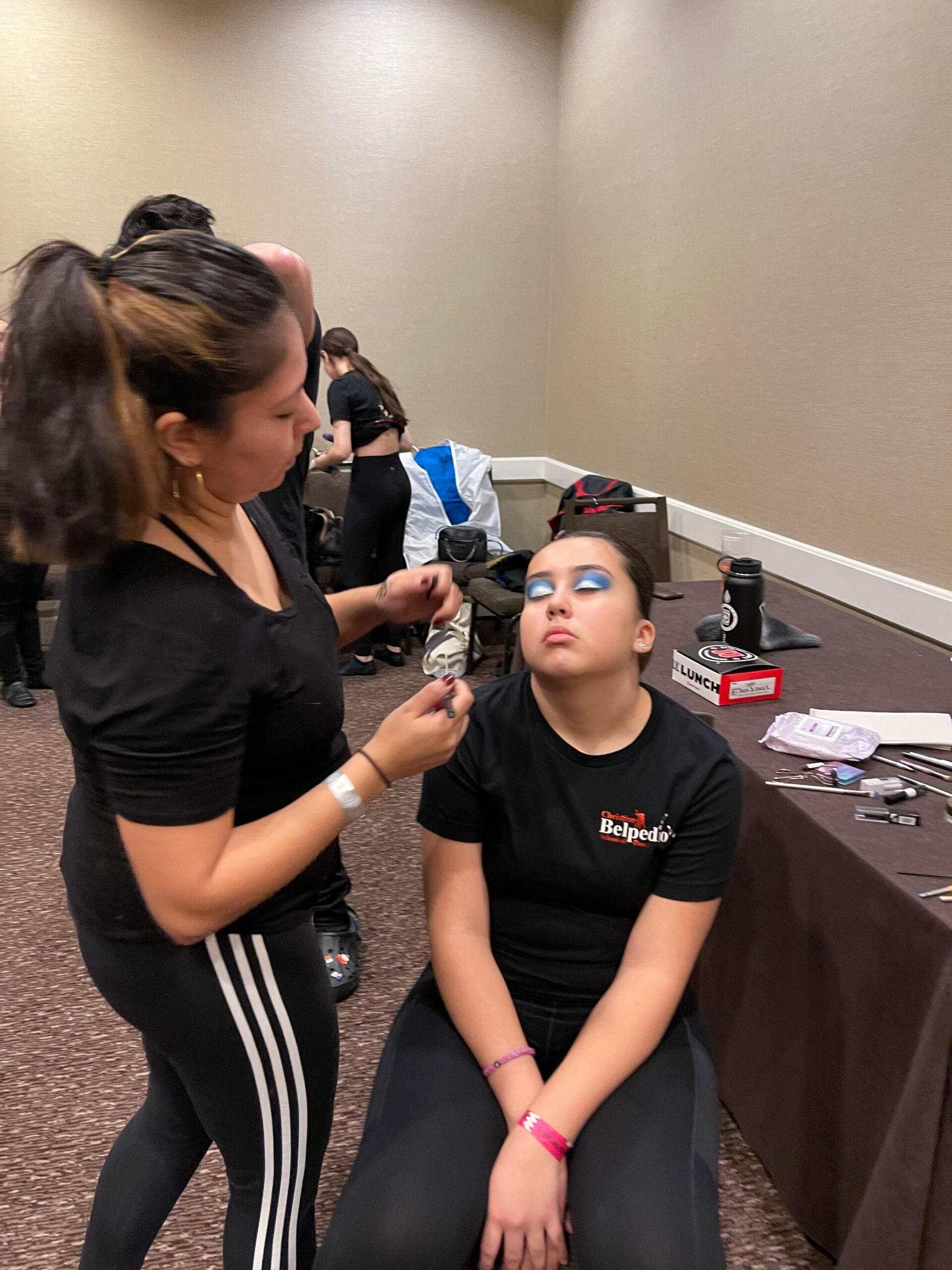 A woman is applying makeup to a young girl 's face.
