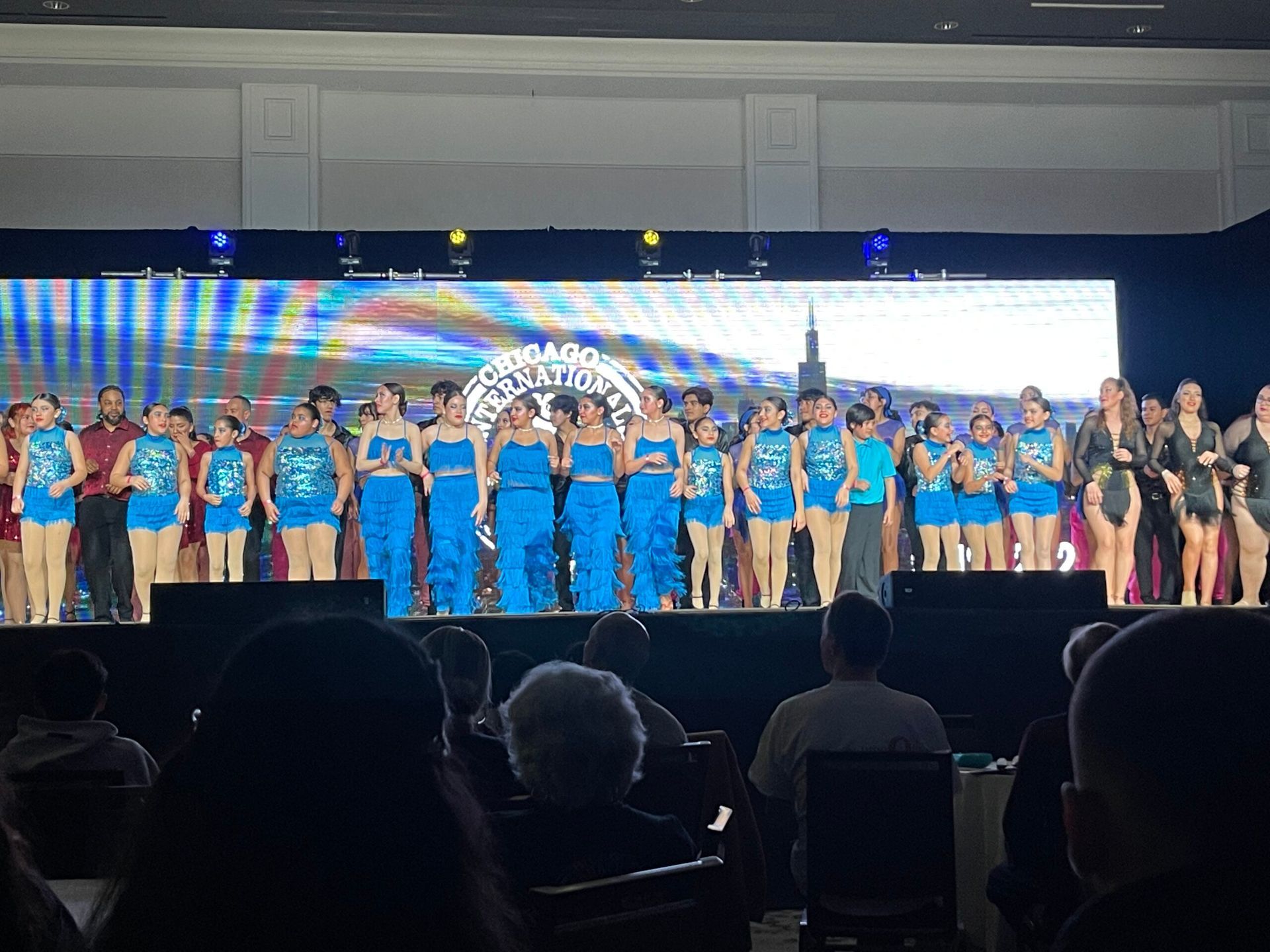 A group of people are standing on a stage in front of a large screen.