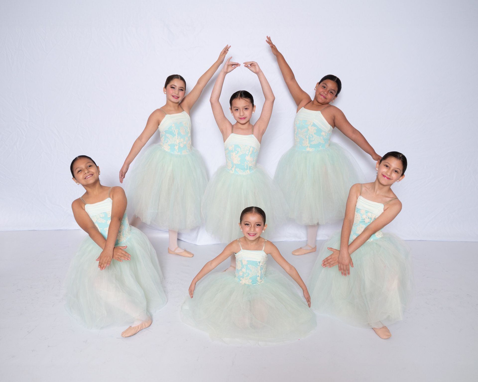 A group of young girls in tutus are posing for a picture.