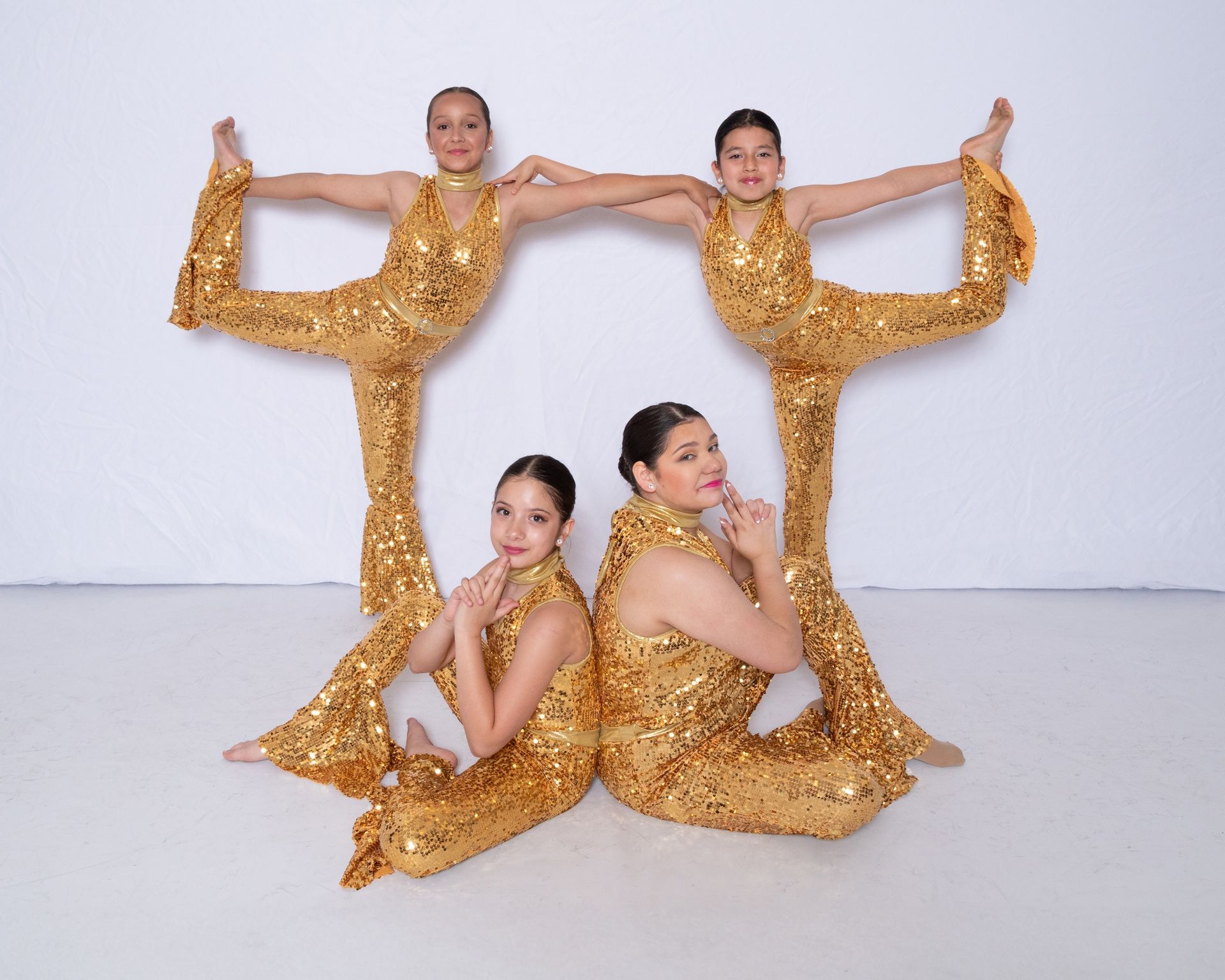 Three girls in gold sequined outfits are posing for a picture