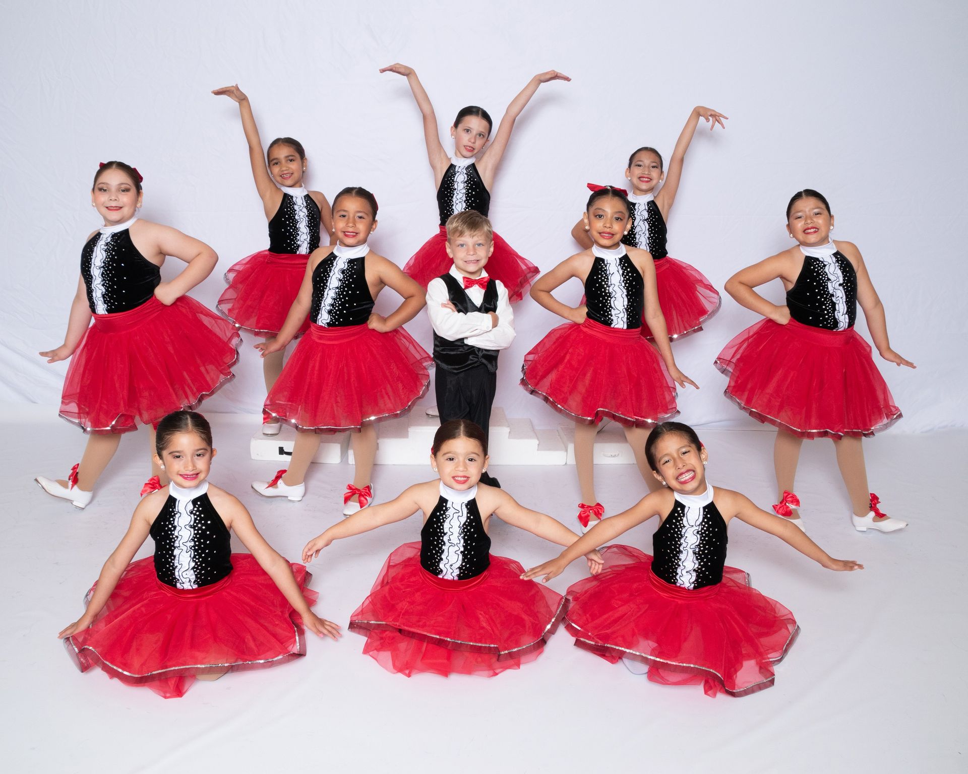 A group of young dancers in red and black tutus are posing for a picture.