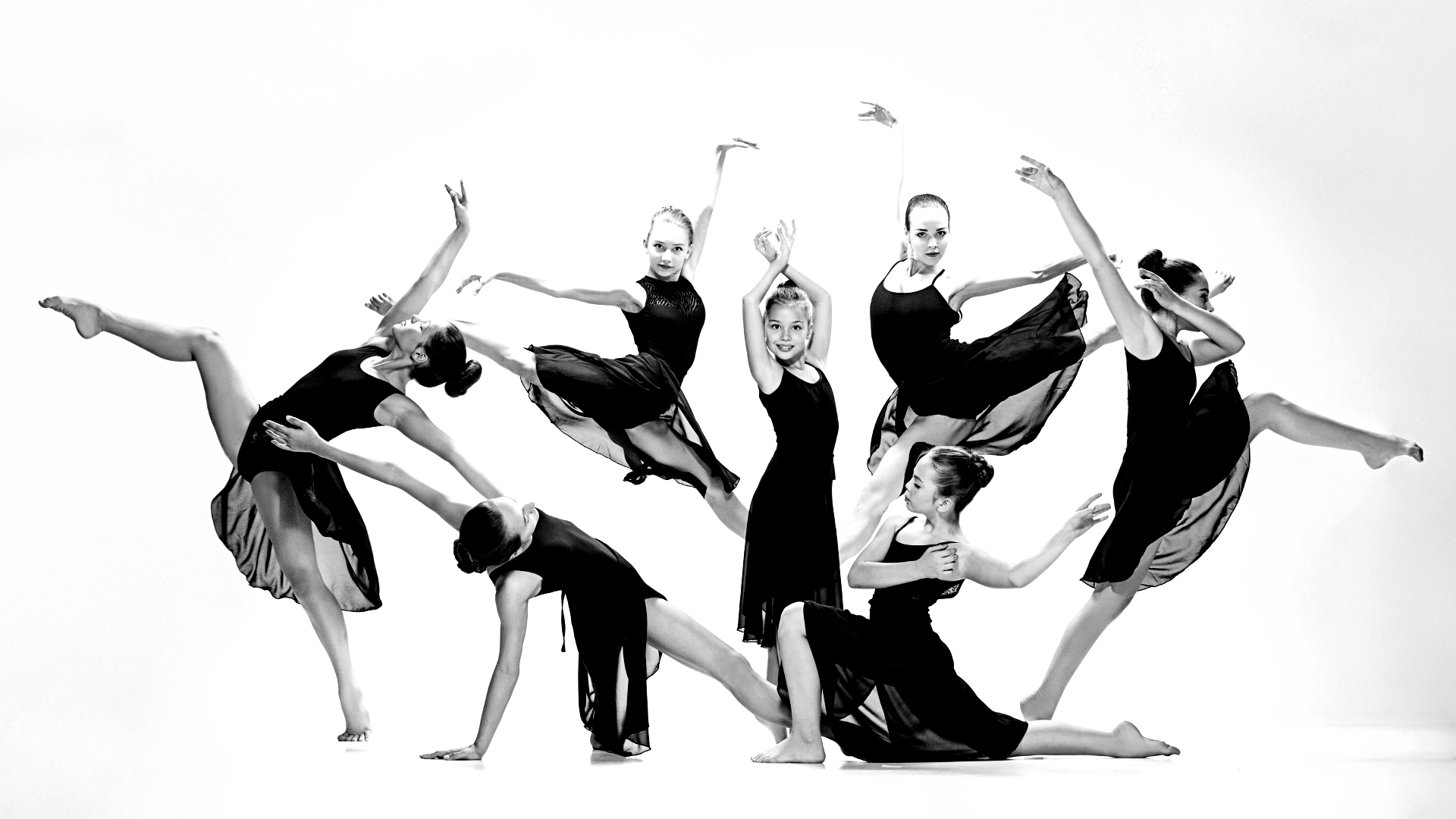 A group of young women are dancing in a black and white photo.