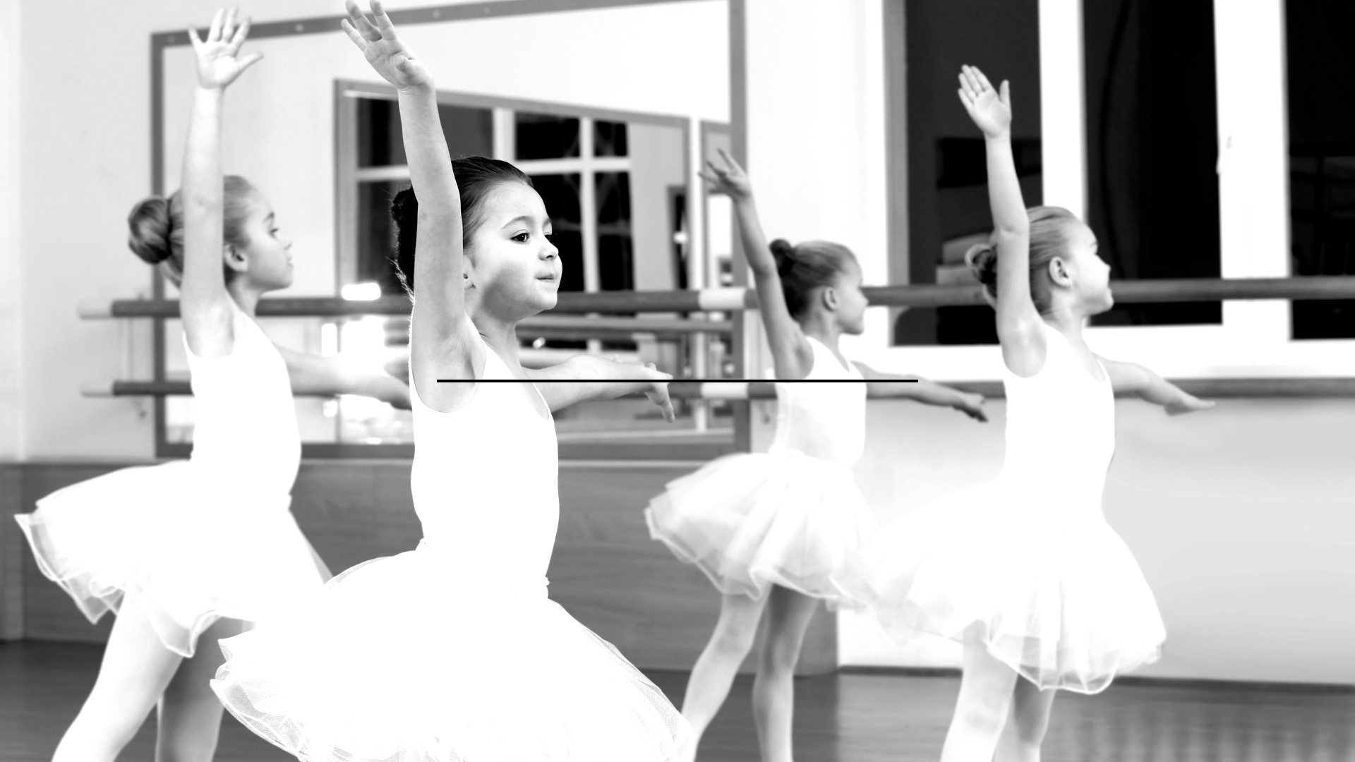 A group of young ballerinas are practicing in a dance studio.