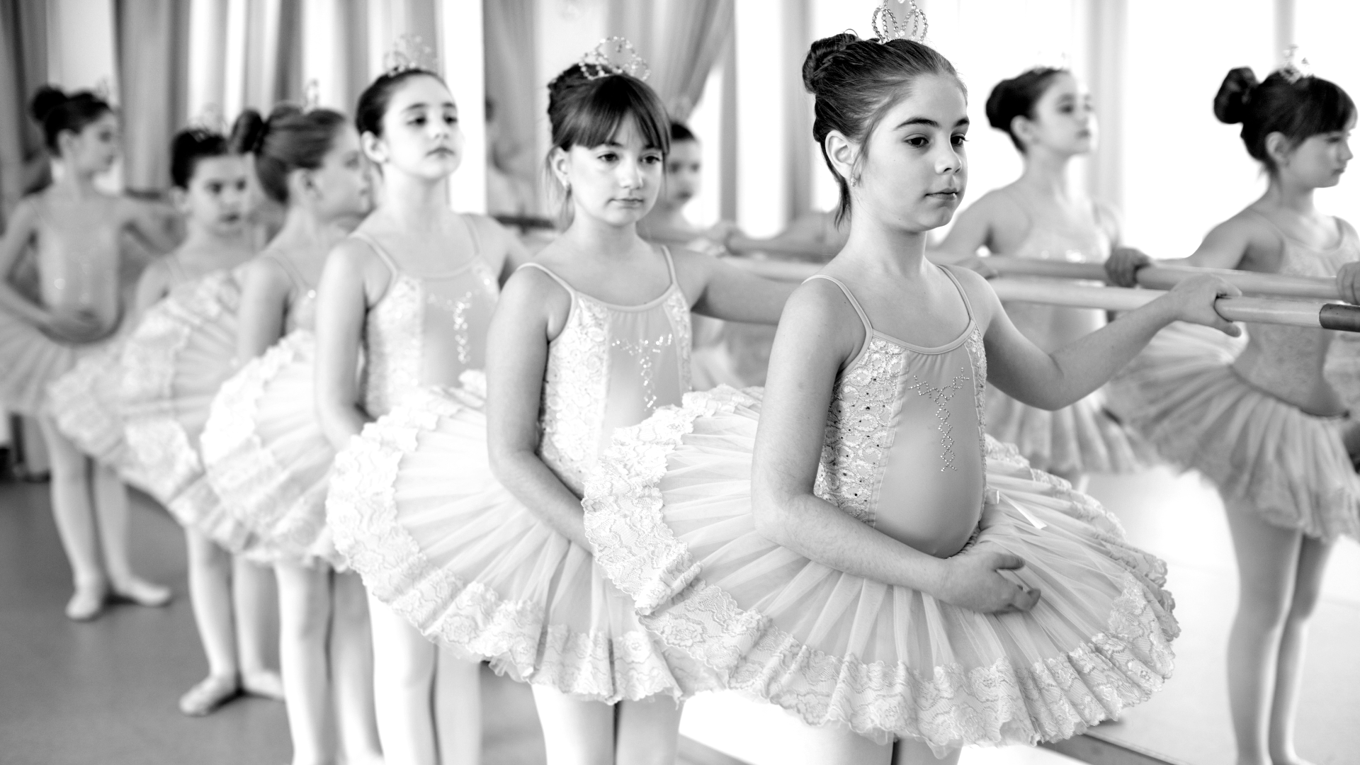 A group of young ballerinas are practicing in a dance studio.