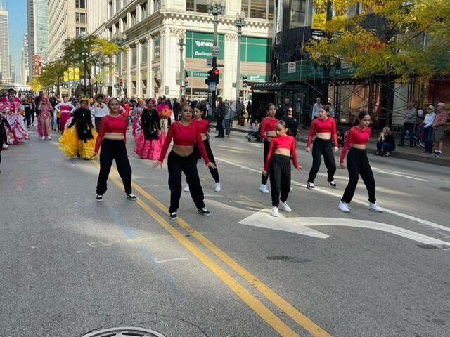A group of people are dancing on the street in a parade.