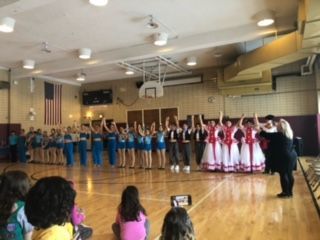 A group of people are standing on a dance floor in a gym.
