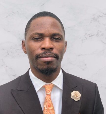 A man in a suit and tie with a flower pin on his lapel