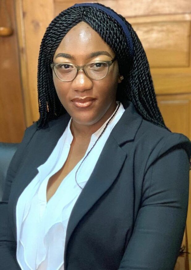 A woman wearing glasses and a black jacket is sitting in a chair.