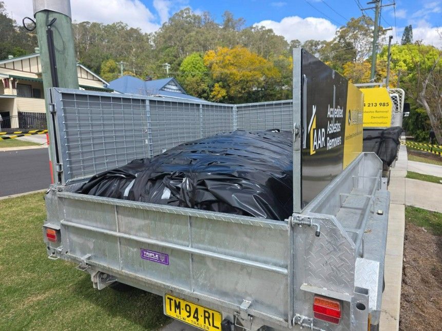 A Trailer Loaded With Black Trash Bags, Parked on a Street — Accredited Asbestos Removers in Ballina, NSW