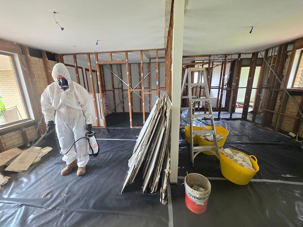 Person in Protective Suit Spraying a Room Under Renovation — Accredited Asbestos Removers in Lismore, NSW