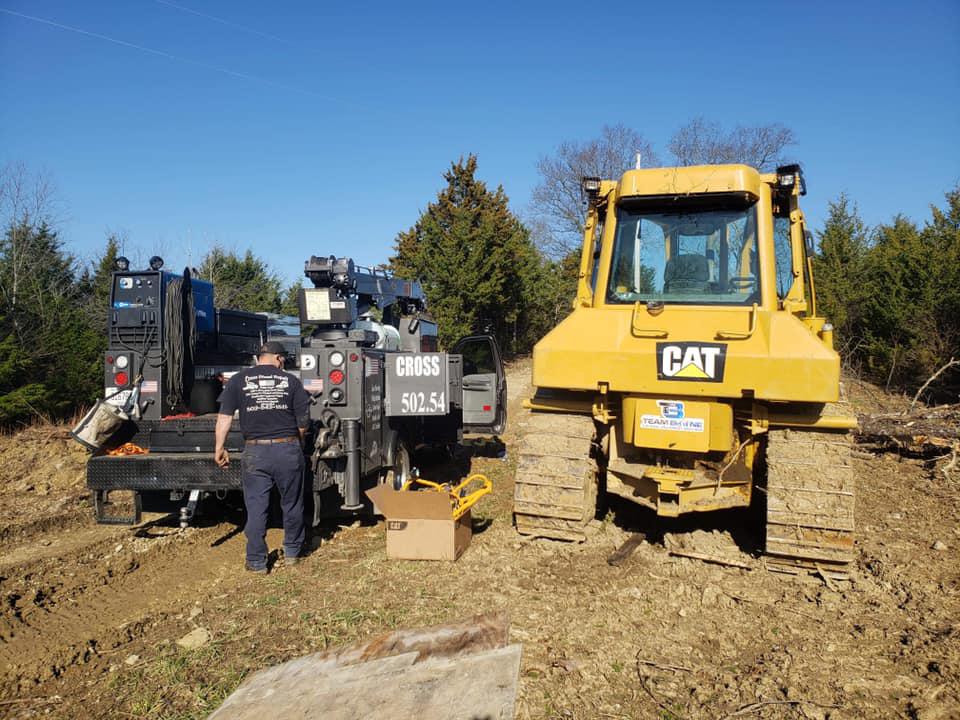 A man is standing next to a yellow cat bulldozer