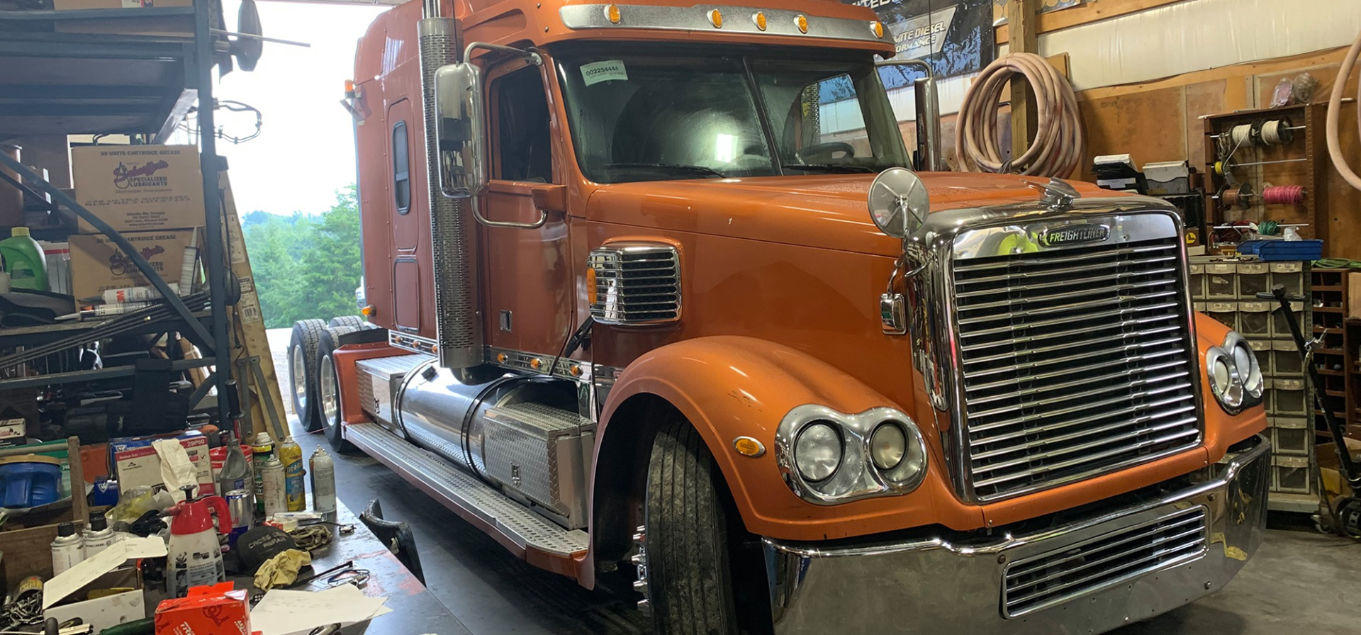 A large orange semi truck is parked in a garage.