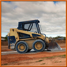 A yellow and blue bulldozer is parked on a dirt road.