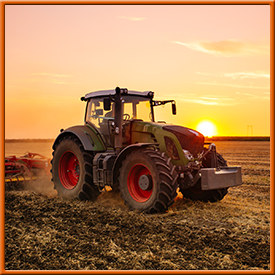 A tractor is plowing a field at sunset.