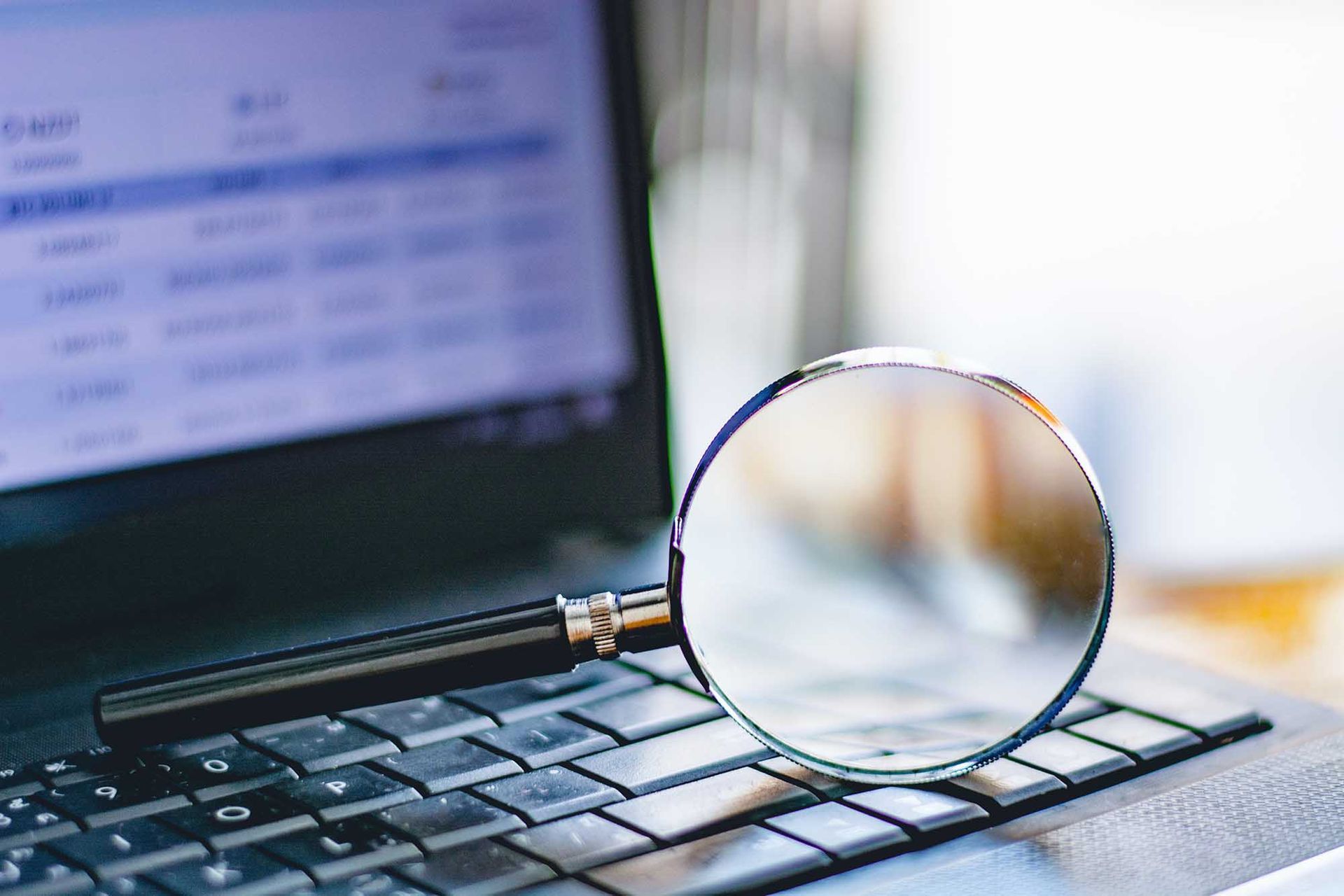 Magnifying glass on laptop keyboard representing investigation and research for matrimonial background checks