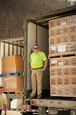 A man in a green shirt is standing in the back of a truck.
