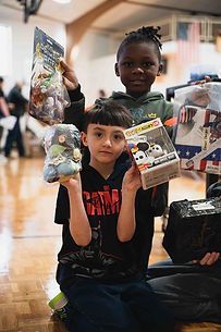 Two young boys are sitting on the floor holding toys.