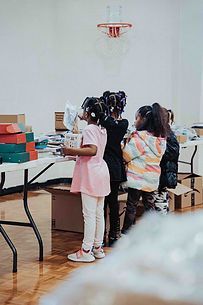 A group of young girls are standing around a table in a room.