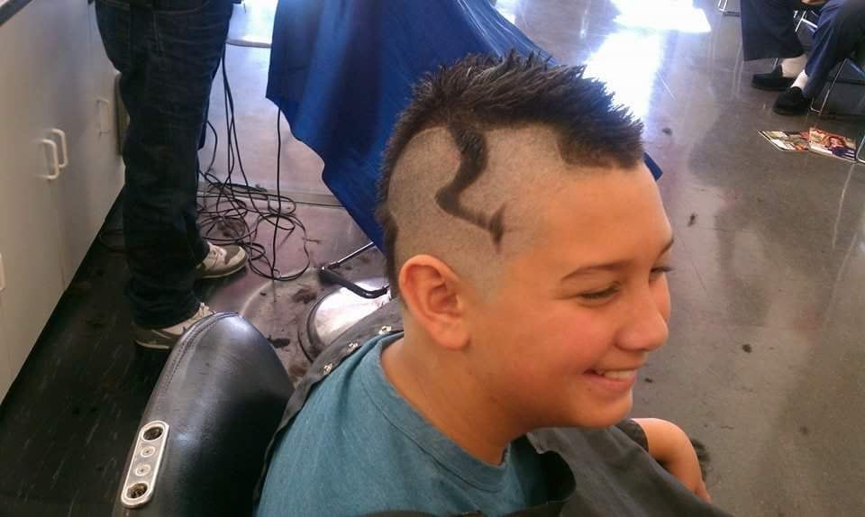 A young boy is getting his hair cut at a barber shop