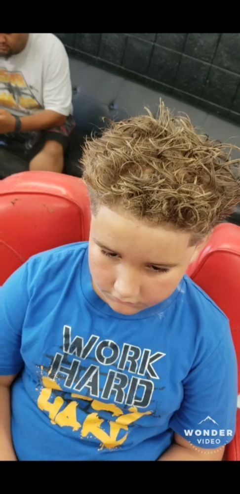 A young boy wearing a blue shirt that says work hard play hard