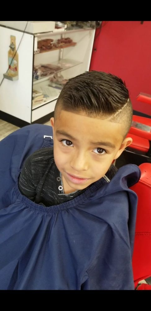 A young boy is getting his hair cut at a barber shop.