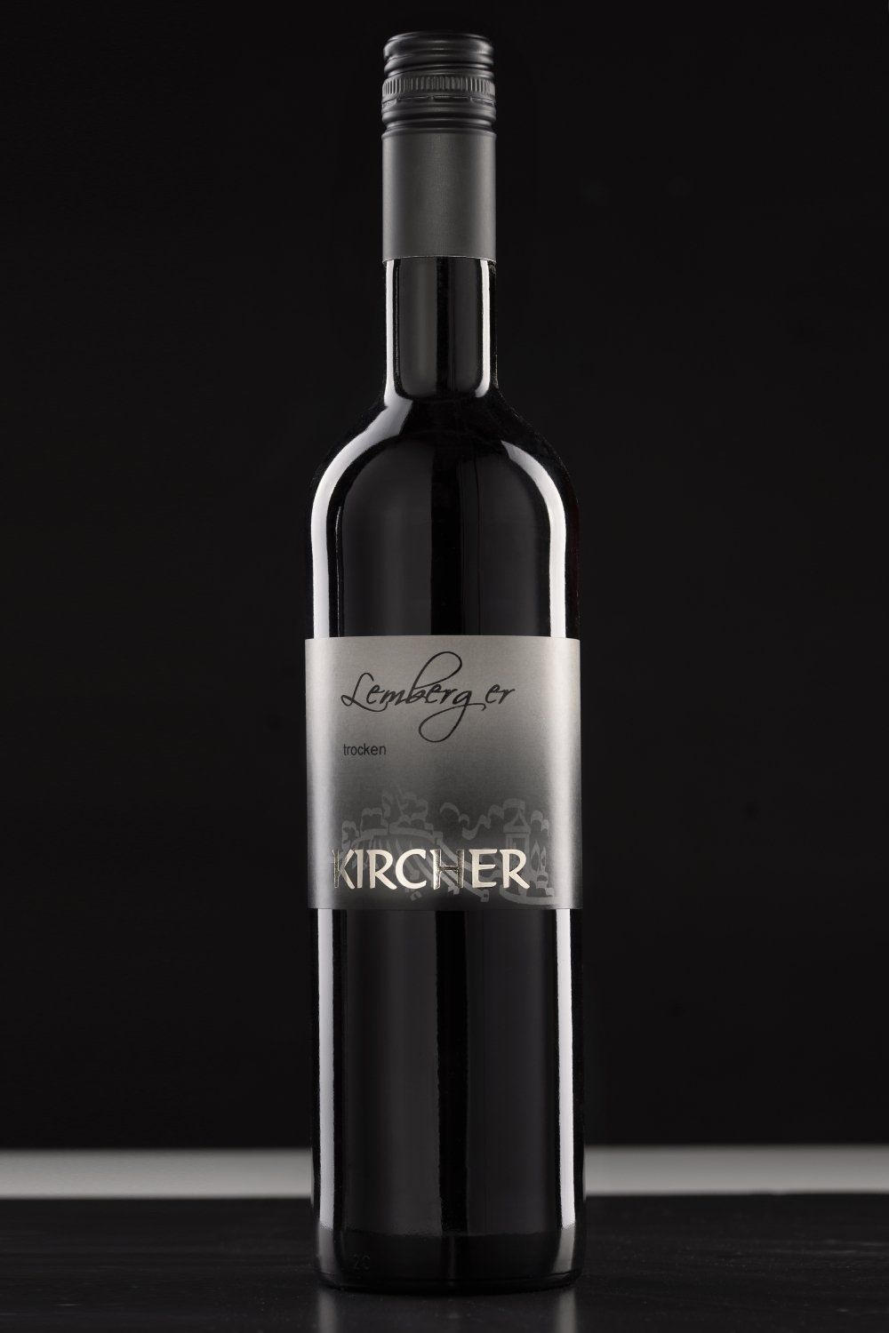 Eine Flasche Wein steht auf einem Tisch vor schwarzem Hintergrund.