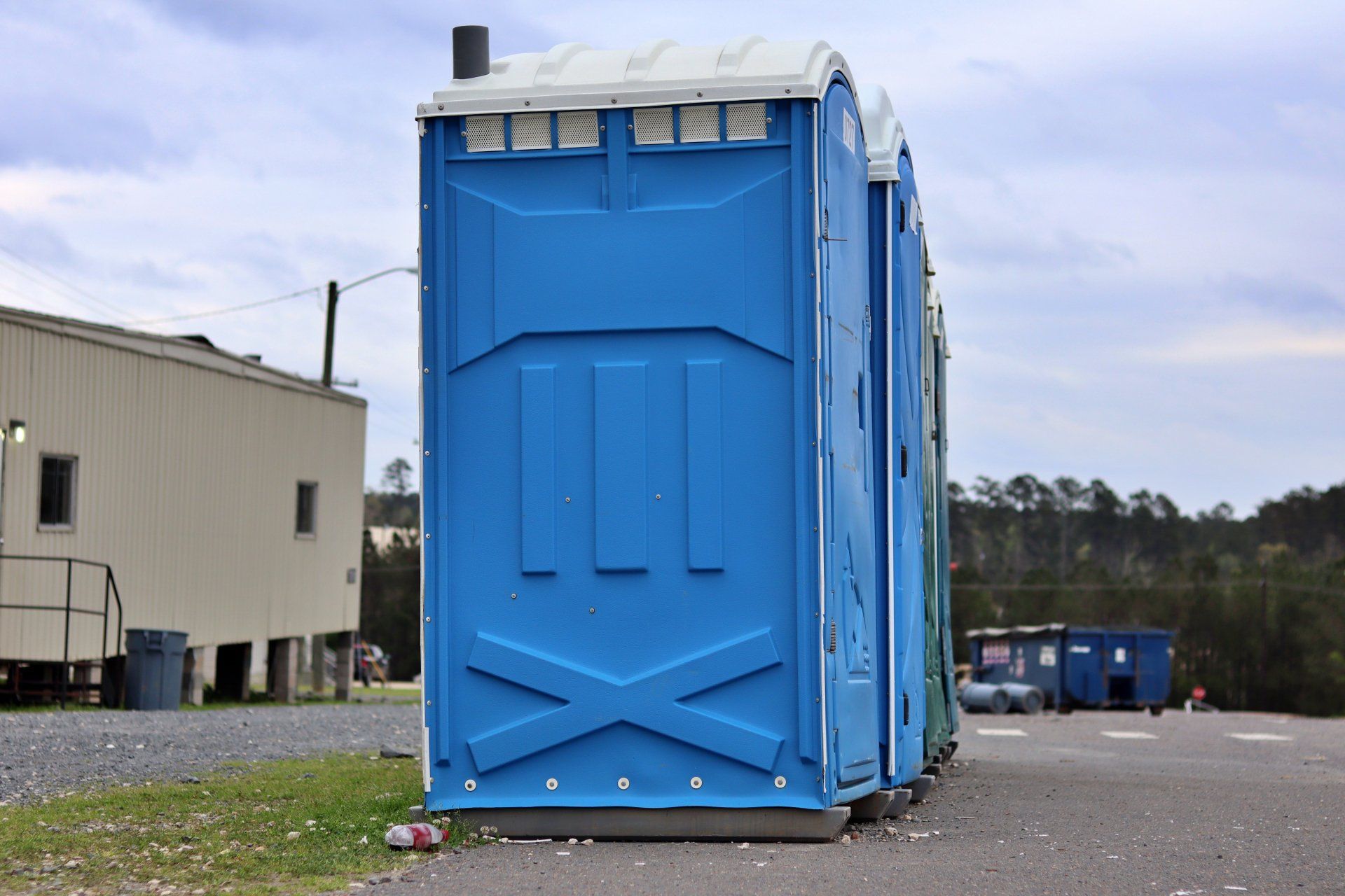 Toilettes portables bleues et vertes alignées sur un parking.