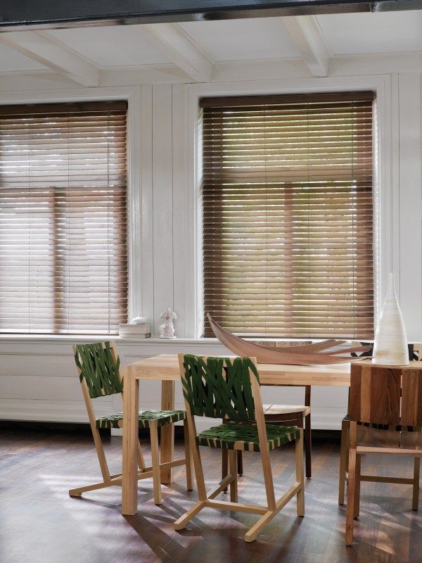 A dining room with a table and chairs and blinds on the windows.