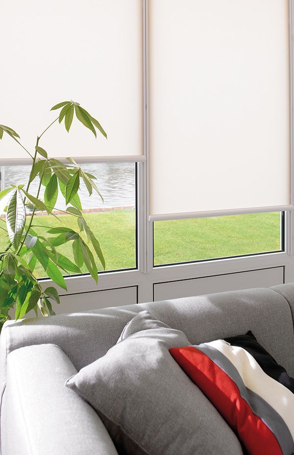 A living room with a couch and a window with white blinds.
